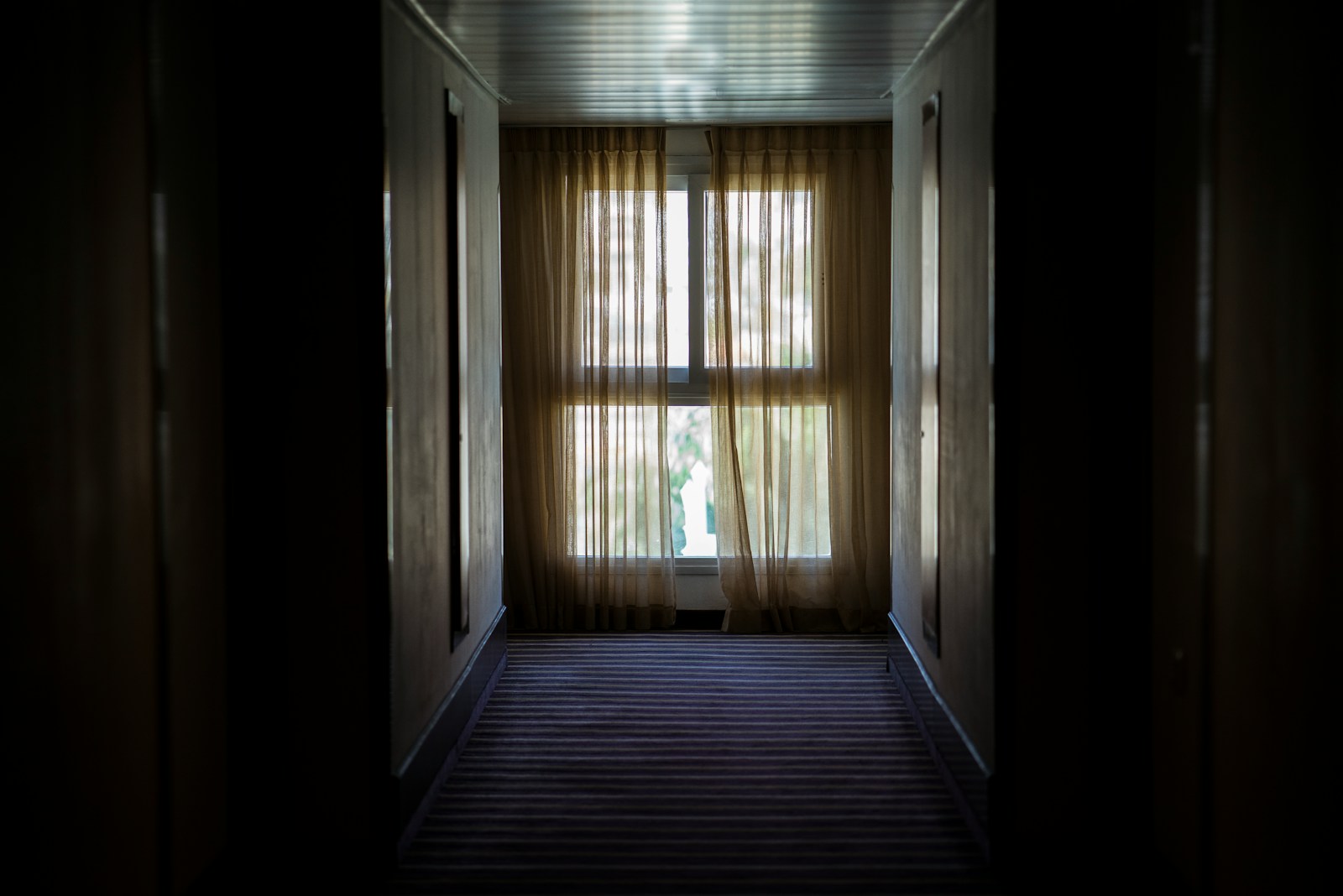 hallway leading to window covered by brown window curtain